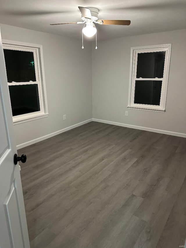 spare room with dark wood-style floors, ceiling fan, and baseboards