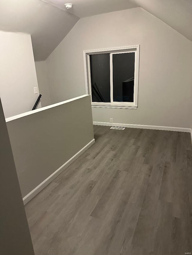 bonus room featuring vaulted ceiling, baseboards, and wood finished floors