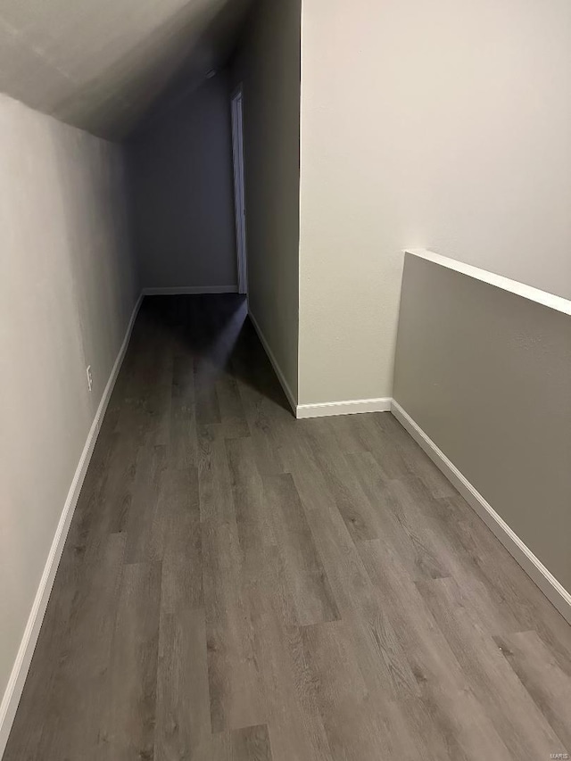 hallway with lofted ceiling, baseboards, and dark wood-style flooring