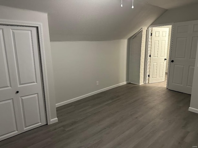 bonus room featuring dark wood-style floors, baseboards, and vaulted ceiling