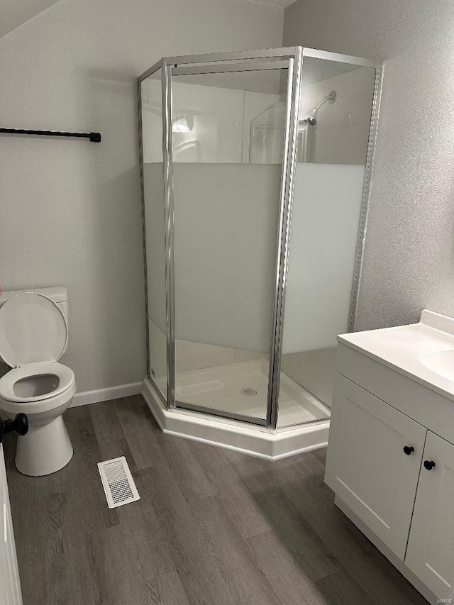 bathroom with visible vents, toilet, a stall shower, vanity, and wood finished floors