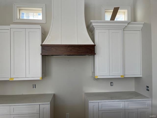 kitchen featuring white cabinetry and custom range hood