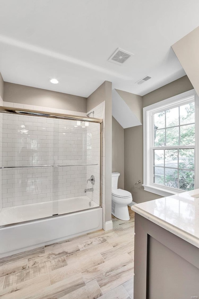 full bathroom with visible vents, toilet, vanity, and shower / bath combination with glass door