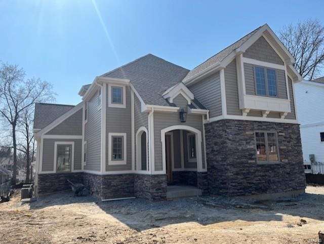 view of front facade with stone siding and roof with shingles