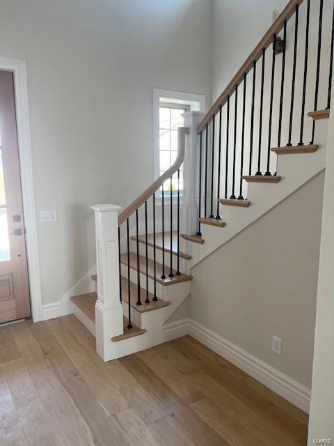 foyer with stairway, baseboards, and wood finished floors