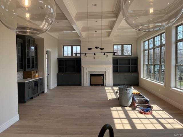 unfurnished living room featuring crown molding, baseboards, beamed ceiling, light wood-type flooring, and coffered ceiling