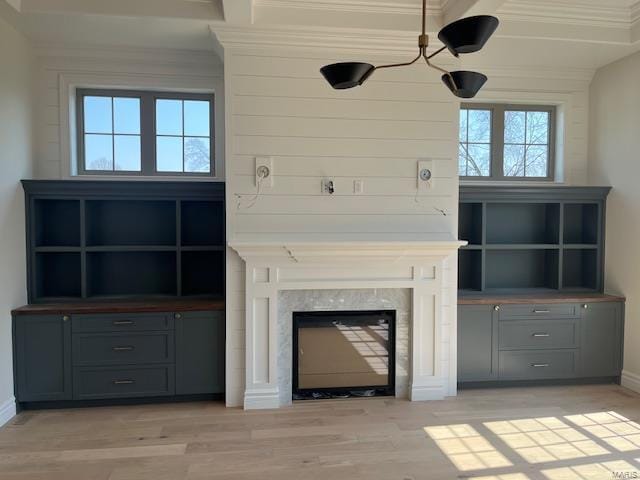 unfurnished living room with light wood finished floors, a fireplace, baseboards, and ornamental molding