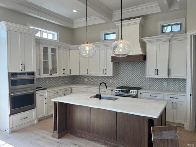 kitchen with beamed ceiling, light countertops, appliances with stainless steel finishes, custom exhaust hood, and a sink