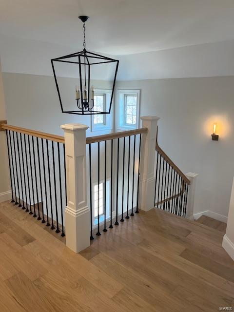 stairway featuring a chandelier, baseboards, and wood finished floors