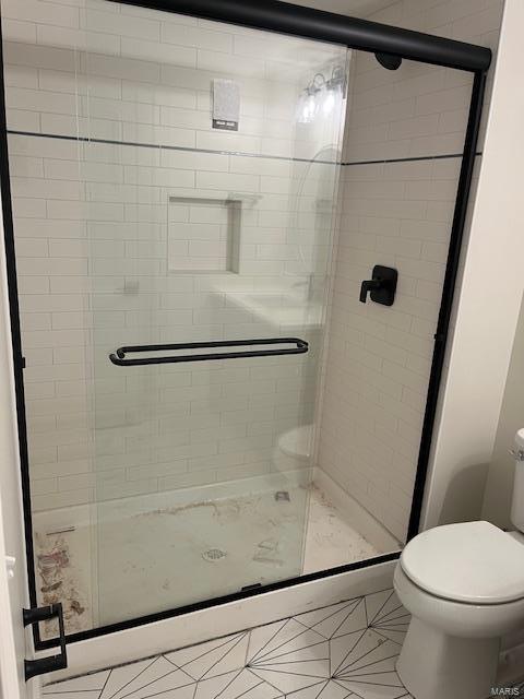 bathroom with tile patterned floors, toilet, and a stall shower