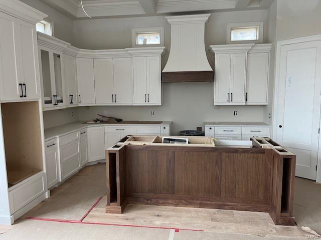 kitchen featuring white cabinets, premium range hood, and a center island