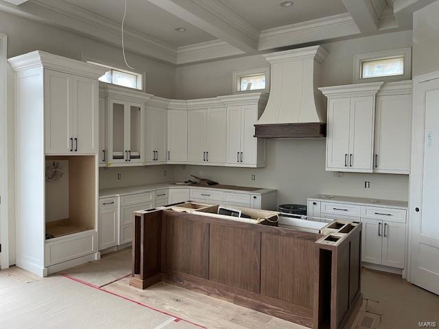 kitchen with premium range hood, beamed ceiling, a kitchen island, and crown molding