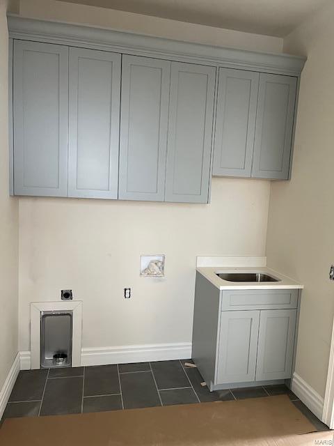 laundry room featuring dark tile patterned floors, cabinet space, and baseboards