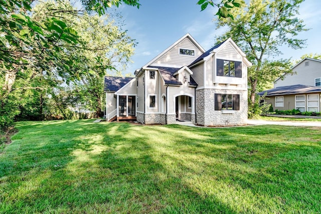 view of front facade with stone siding and a front lawn