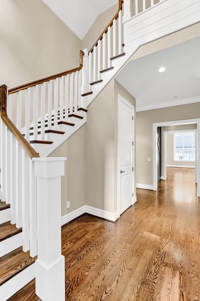 stairs featuring crown molding, baseboards, lofted ceiling, recessed lighting, and wood finished floors