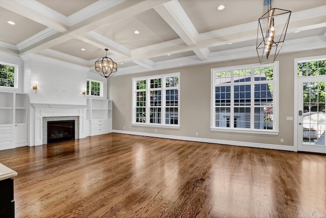 unfurnished living room with beam ceiling, wood finished floors, a fireplace, baseboards, and a chandelier