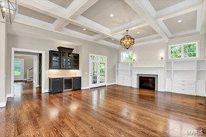 unfurnished living room with a wealth of natural light, a fireplace, an inviting chandelier, and wood finished floors