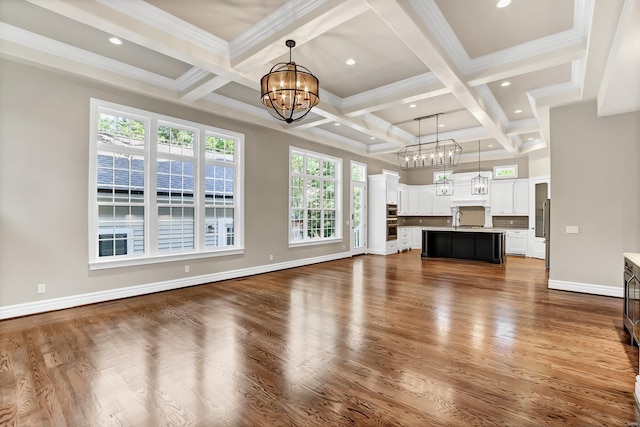 unfurnished living room featuring beam ceiling, dark wood-type flooring, a sink, baseboards, and a chandelier