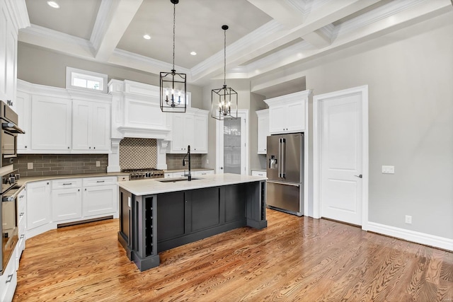 kitchen with beam ceiling, a sink, white cabinetry, appliances with stainless steel finishes, and light wood finished floors