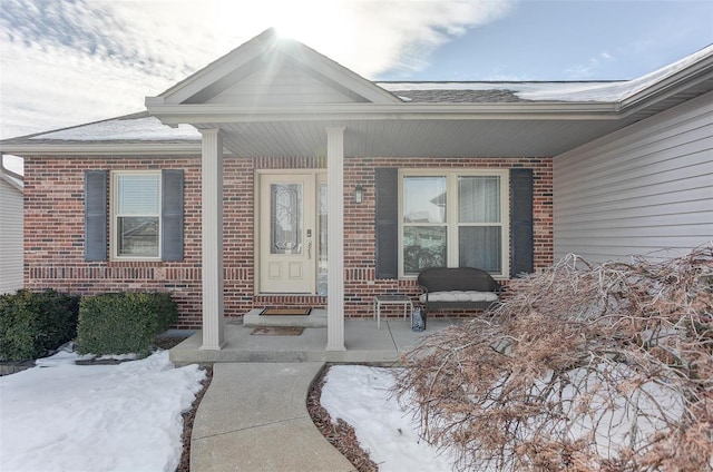 snow covered property entrance with covered porch