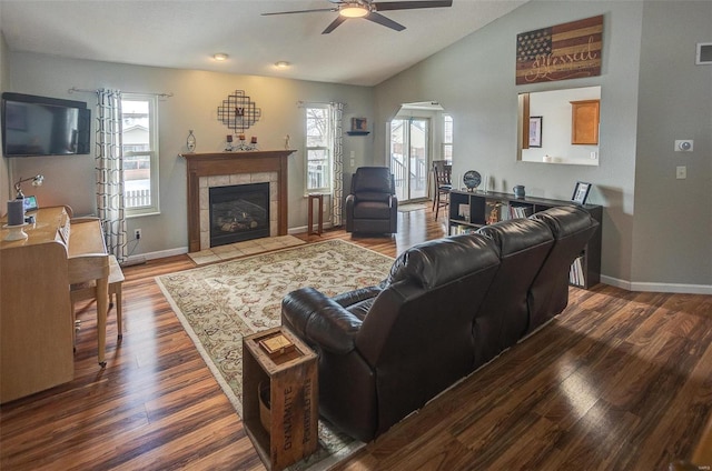 living room featuring ceiling fan, wood-type flooring, a fireplace, and vaulted ceiling