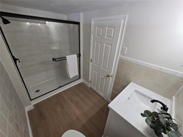 bathroom with vanity, an enclosed shower, hardwood / wood-style floors, and tile walls