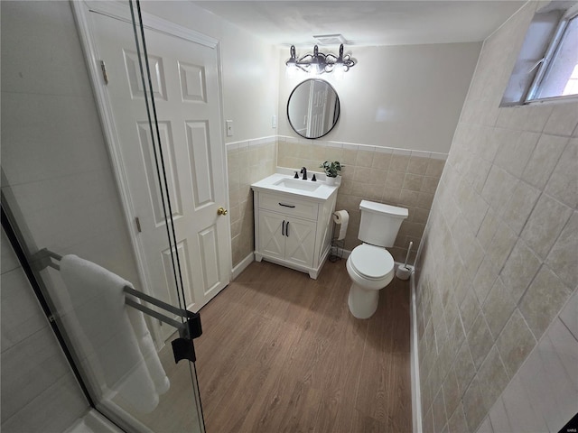 bathroom with tile walls, vanity, wood-type flooring, and toilet