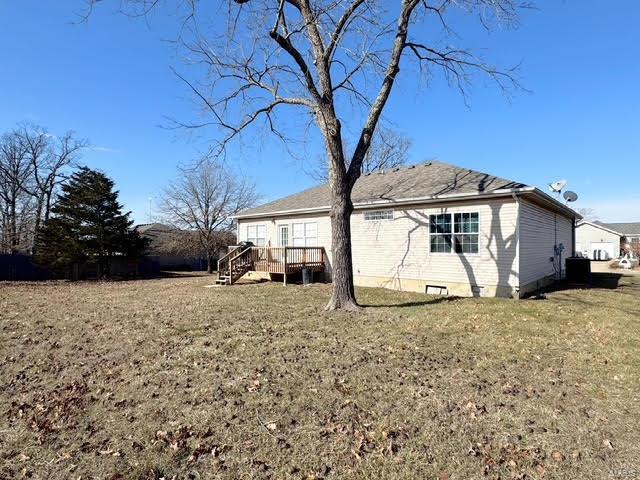 rear view of property featuring a wooden deck and a yard