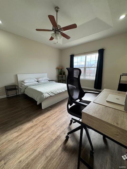 bedroom featuring ceiling fan, hardwood / wood-style flooring, and a raised ceiling