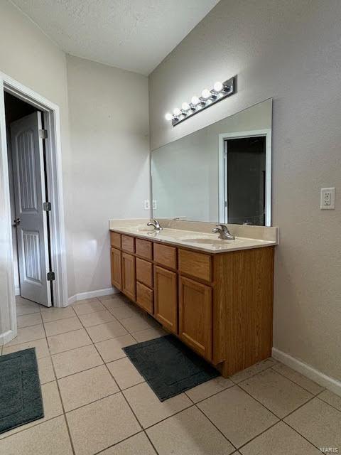 bathroom with a textured ceiling, tile patterned floors, and vanity