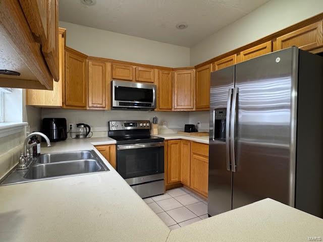 kitchen with sink, stainless steel appliances, and light tile patterned flooring