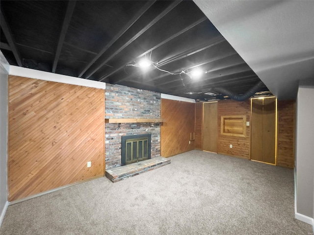 basement with a brick fireplace, carpet floors, and wooden walls