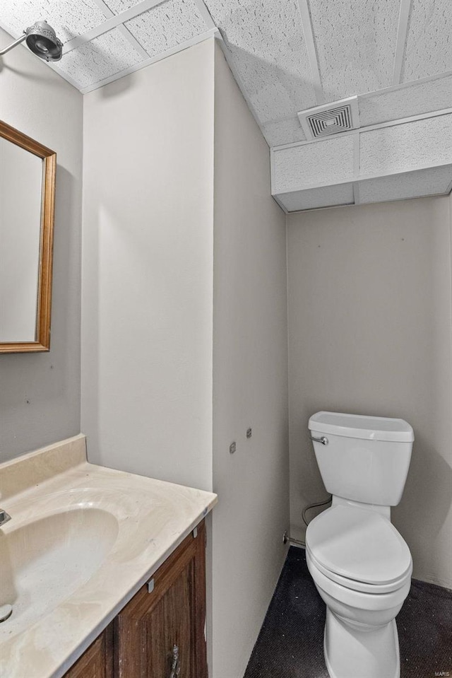 bathroom featuring a drop ceiling, vanity, and toilet