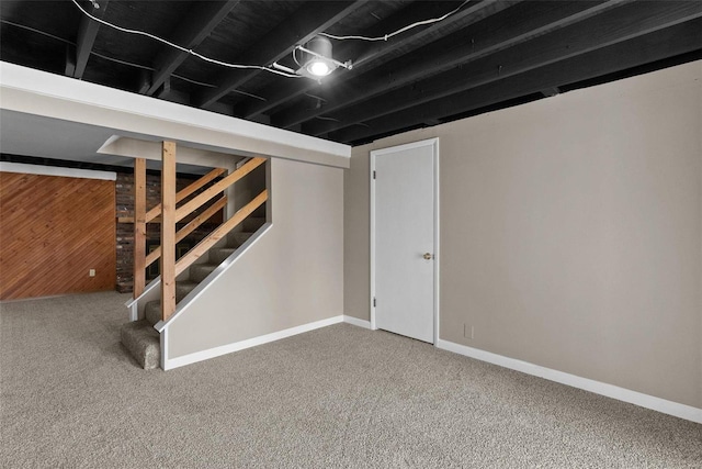 basement featuring carpet flooring and wood walls