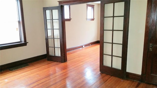 spare room featuring hardwood / wood-style floors, french doors, and a healthy amount of sunlight