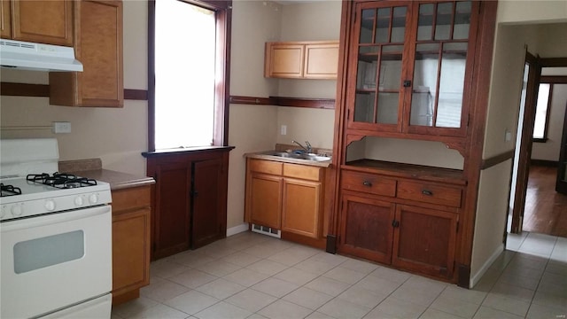 kitchen featuring plenty of natural light, sink, gas range gas stove, and light tile patterned floors