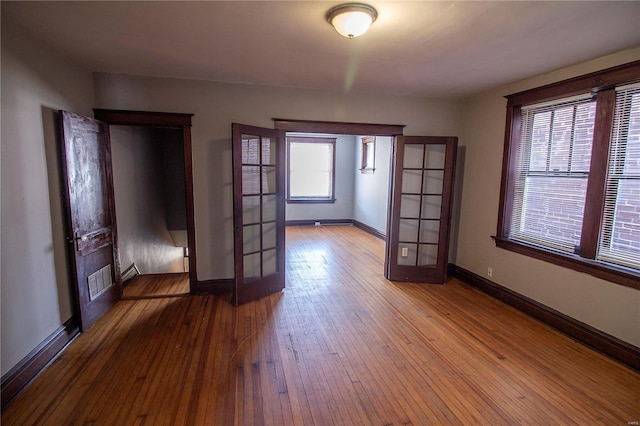 spare room featuring hardwood / wood-style flooring, plenty of natural light, french doors, and a baseboard radiator