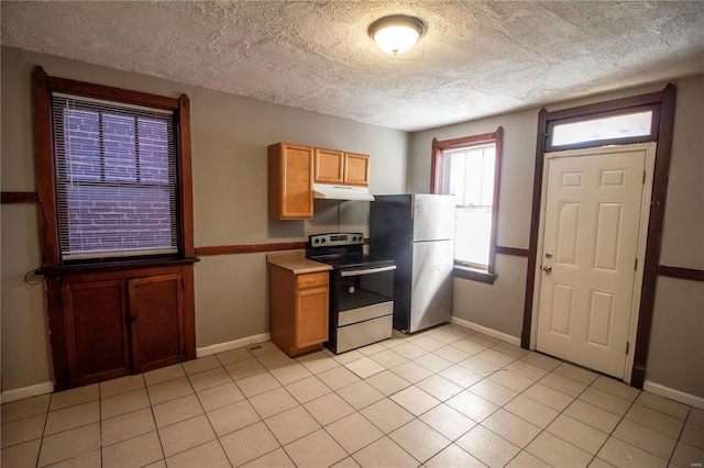 kitchen with stainless steel appliances, light tile patterned floors, and a textured ceiling