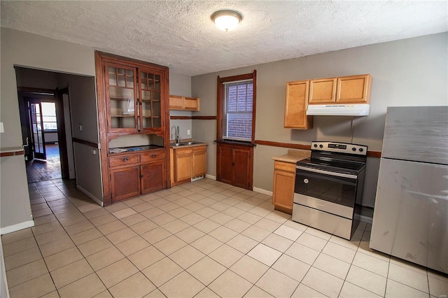 kitchen featuring sink, light tile patterned floors, stainless steel range with electric stovetop, a textured ceiling, and white fridge