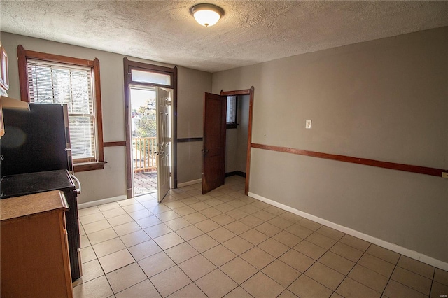 kitchen featuring light tile patterned floors, a textured ceiling, and stainless steel refrigerator