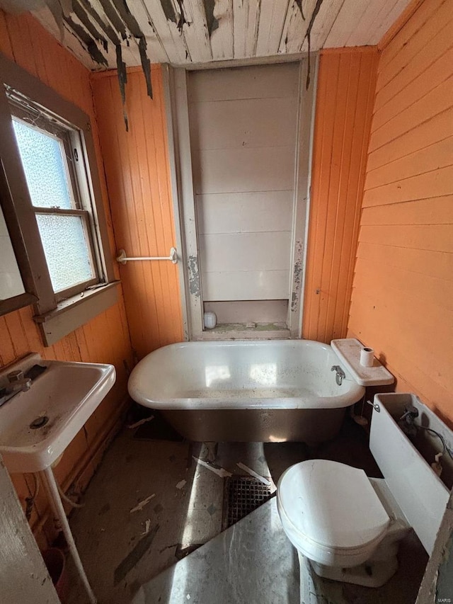 bathroom featuring a bathtub, sink, and wooden walls