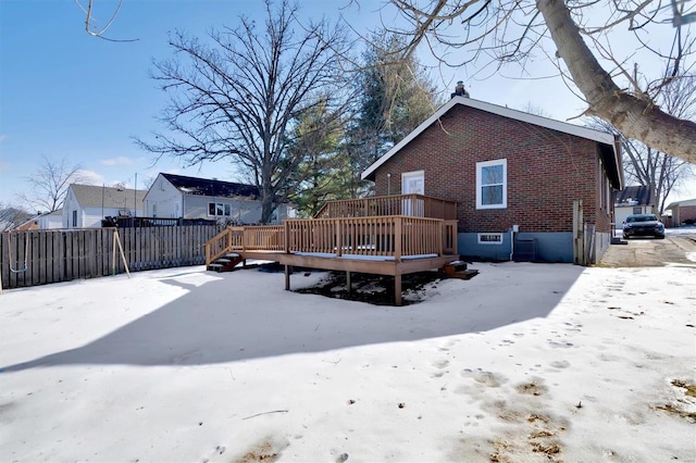 snow covered back of property with a wooden deck