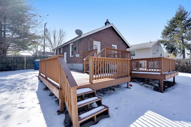 snow covered back of property featuring a wooden deck