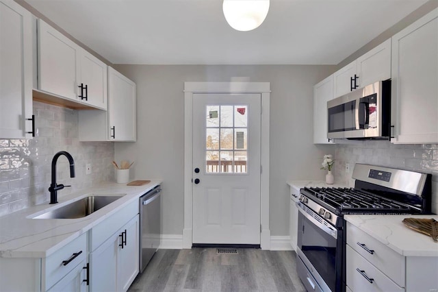 kitchen featuring tasteful backsplash, stainless steel appliances, sink, and white cabinets