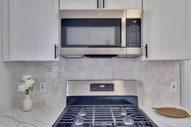 kitchen featuring white cabinetry, decorative backsplash, light stone countertops, and appliances with stainless steel finishes