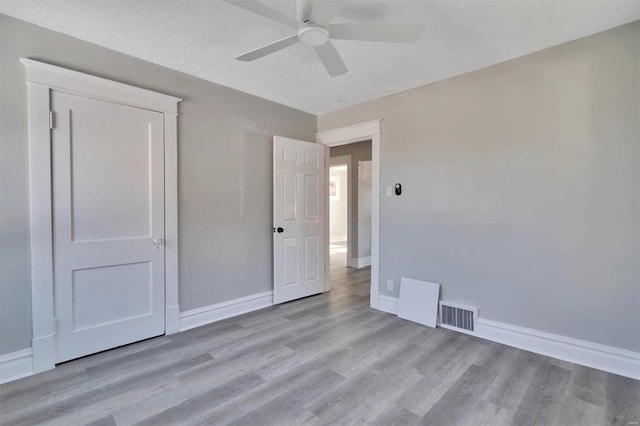 unfurnished bedroom with a textured ceiling, light hardwood / wood-style floors, and ceiling fan