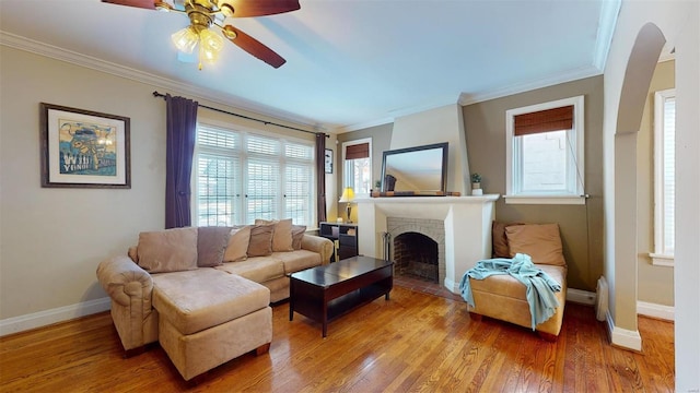 living room with hardwood / wood-style flooring, a fireplace, ornamental molding, and ceiling fan