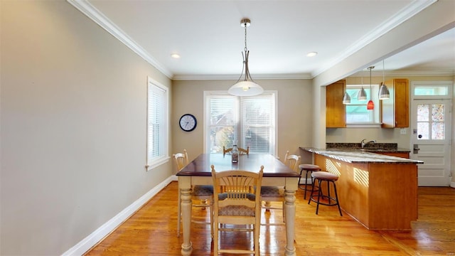 dining area with ornamental molding and light hardwood / wood-style floors