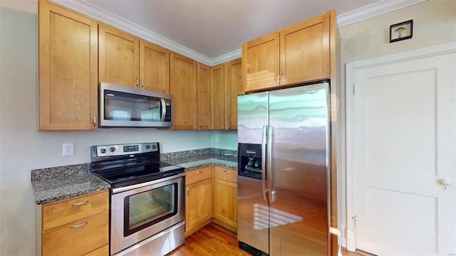 kitchen featuring stainless steel appliances, crown molding, dark stone countertops, and light hardwood / wood-style flooring