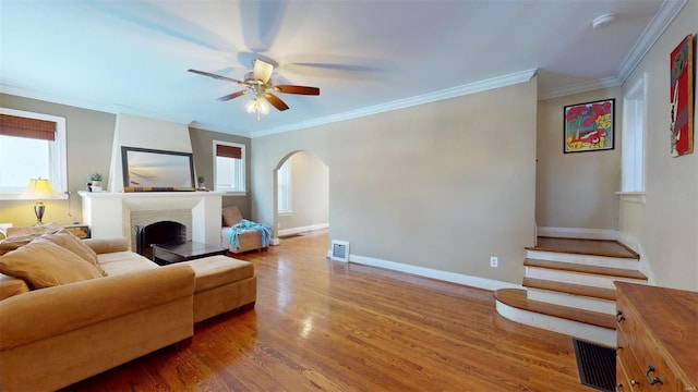 living room with hardwood / wood-style flooring, ornamental molding, and ceiling fan